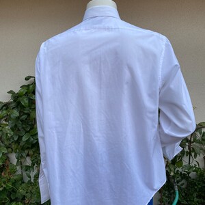 May include: A white long-sleeved button-down shirt with a classic collar. The shirt is made of a smooth, wrinkle-resistant fabric.