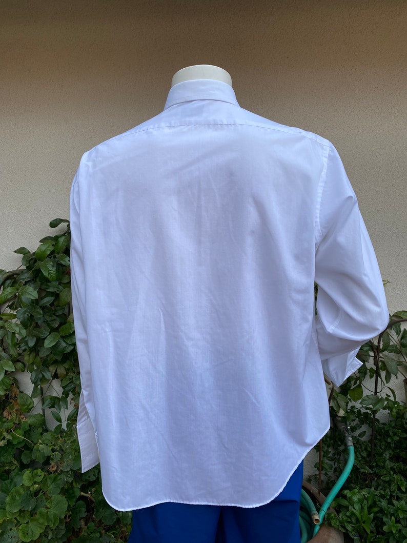 May include: A white long-sleeved button-down shirt with a classic collar. The shirt is made of a smooth, wrinkle-resistant fabric.