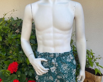 May include: Green and white patterned swim trunks with a floral design.