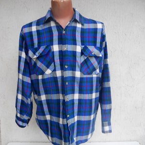 May include: A blue, white, green, and red plaid long-sleeve button-down shirt with two chest pockets.