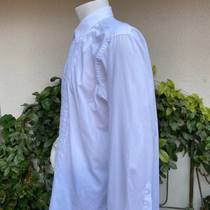 May include: A white long-sleeve dress shirt with a pleated front and a button-down collar.