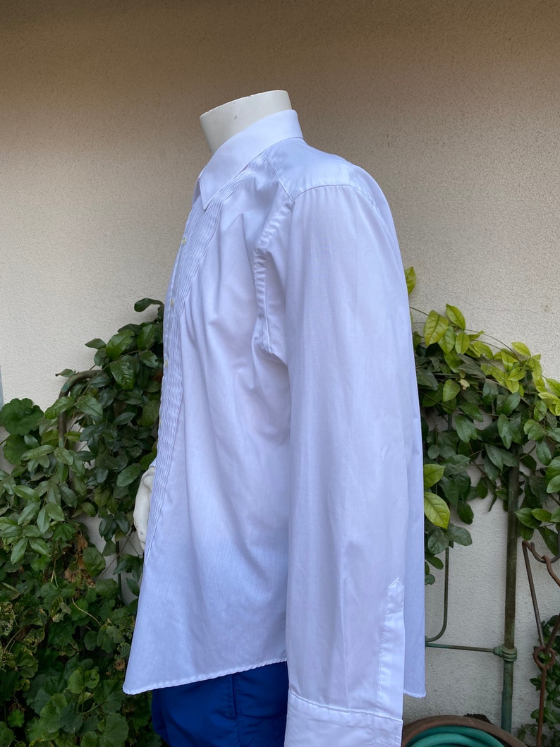 May include: A white long-sleeve dress shirt with a pleated front and a button-down collar.
