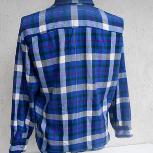 May include: A long-sleeved plaid shirt in blue, white, green, and red. The shirt has a button-down collar and a button-up front.