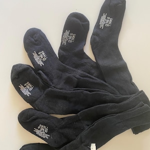 May include: Five pairs of black socks are displayed on a white surface. Each sock has a label that reads "SMALL 9-9 1/2-10". The socks are made of a soft material and are folded.