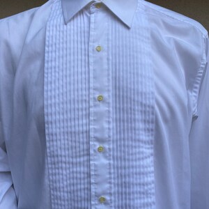 May include: A white dress shirt with a pleated front and a button-down collar.