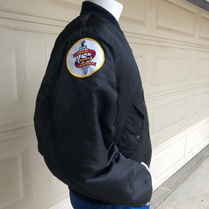 May include: Black bomber jacket with a yellow and red embroidered patch on the left sleeve. The patch features a skull with a sword and the text "Death Before Dishonor".