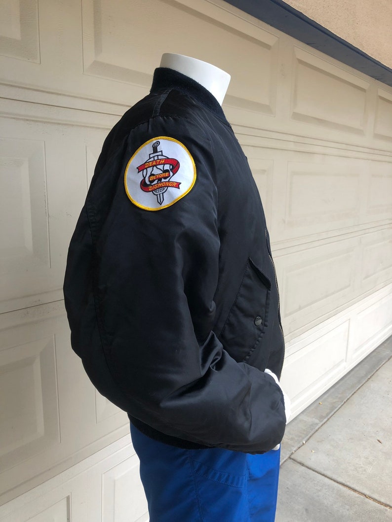 May include: Black bomber jacket with a yellow and red embroidered patch on the left sleeve. The patch features a skull with a sword and the text "Death Before Dishonor".