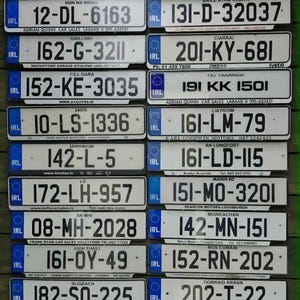 Könnte beinhalten: Eine Sammlung von achtundzwanzig rechteckigen, weißen irischen Kfz-Kennzeichen, die in einem Raster angeordnet sind. Jedes Schild zeigt schwarze alphanumerische Zeichen, ein blaues EU-Symbol mit den Buchstaben IRL und irische Grafschaftsnamen.