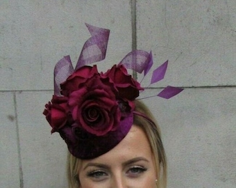 May include: A burgundy velvet hat with a cluster of burgundy roses and purple feathers.
