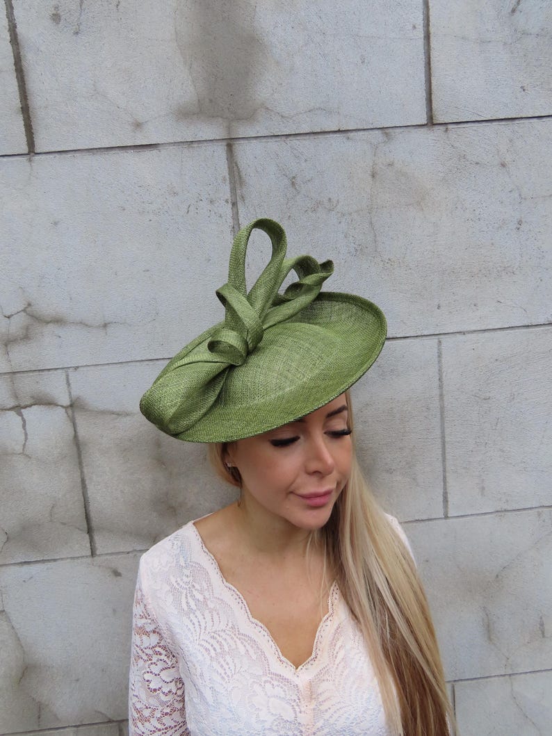 May include: A light green, wide-brimmed hat with a decorative bow. The hat is made of a woven material and has a slightly textured appearance. The hat is a stylish accessory, suitable for special occasions.