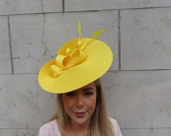 May include: A bright yellow hat with a large brim and a bow. The hat is made of straw and has a feather accent.