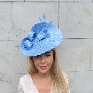 May include: A light blue wide-brimmed hat with a large bow and feathers.