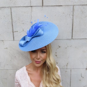 May include: A light blue wide-brimmed hat with a matching bow and feather accent. The hat is made of straw and has a slightly curved brim.