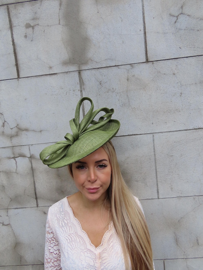 May include: A light green, wide-brimmed hat with a decorative bow. The hat is made of a woven material and has a structured design. The hat is a stylish accessory, suitable for special occasions.