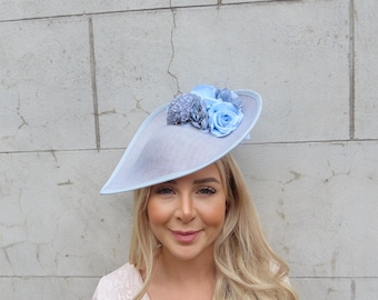 May include: A light blue hat with a flower embellishment. The hat is made of a delicate material and has a wide brim. The flower embellishment is made of blue and white flowers.