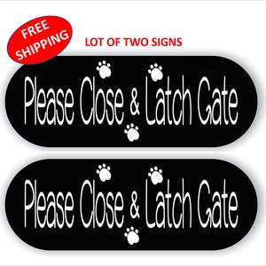 May include: Two black oval signs with white paw prints and the text "Please Close & Latch Gate" in white.