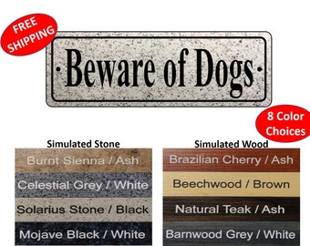 May include: A rectangular sign with the text "Beware of Dogs" in black lettering on a white background with a simulated stone texture. The sign is available in 8 color choices, including Burnt Sienna / Ash, Celestial Grey / White, Solarius Stone / Black, Mojave Black / White, Brazilian Cherry / Ash, Beechwood / Brown, Natural Teak / Ash, and Barnwood Grey / White.