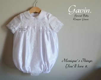 Könnte beinhalten: Weißes Satin-Baby-Stramplerkleid mit Spitzenbesatz und Peter-Pan-Kragen. Das Kleid hängt an einem Holzbügel. Der Text "Gavin. Special Baby Romper Gown. Monique's Things. You'll love it." ist auf weißem Hintergrund gedruckt.