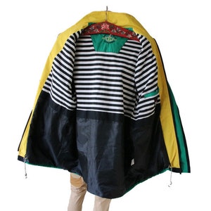 May include: A yellow, green, and black jacket with a striped lining. The jacket has a zipper closure and a hood.