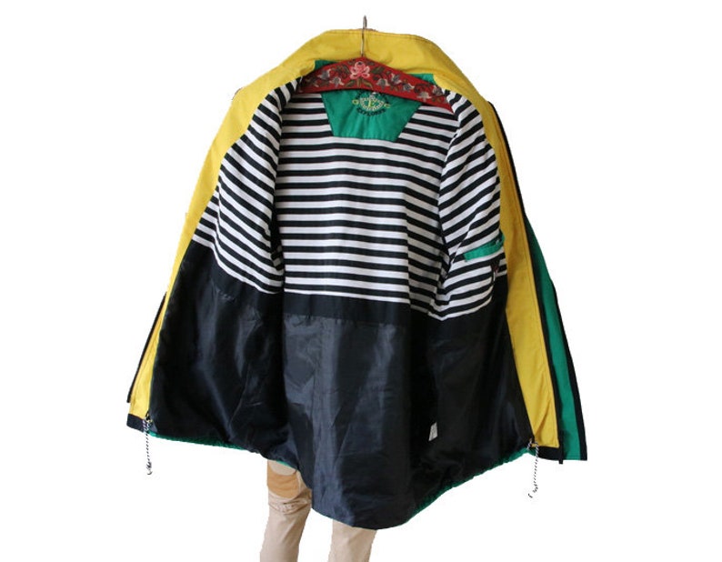 May include: A yellow, green, and black jacket with a striped lining. The jacket has a zipper closure and a hood.
