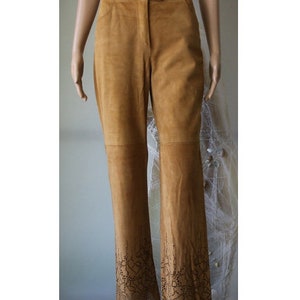 May include: Brown suede pants with a flared leg and a lace-like design at the bottom.