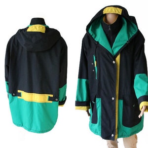May include: A black, green, and yellow hooded jacket with a zipper closure and multiple pockets. The jacket has a contrasting color design with a green and yellow stripe across the bottom.