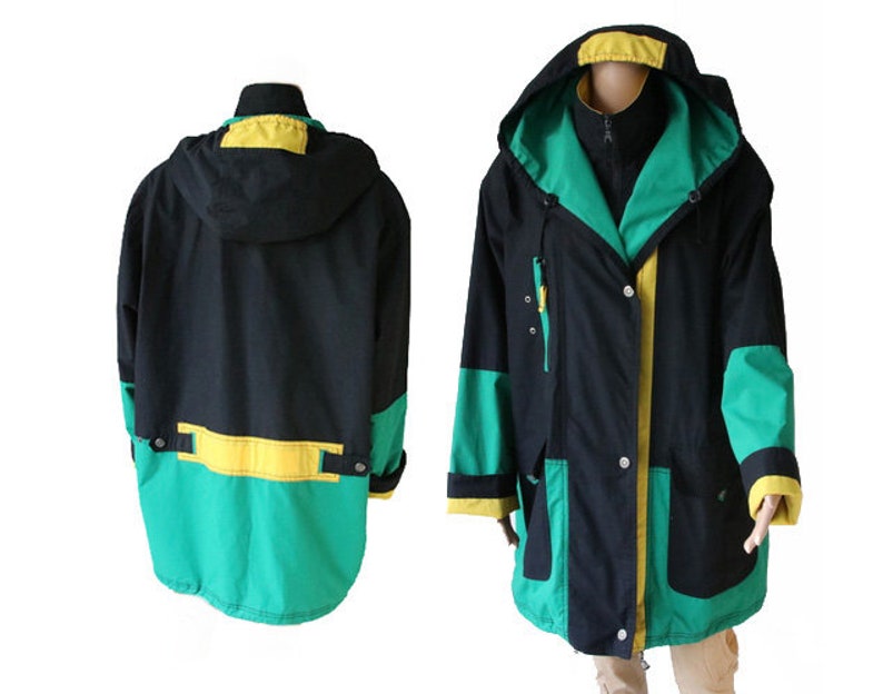 May include: A black, green, and yellow hooded jacket with a zipper closure and multiple pockets. The jacket has a contrasting color design with a green and yellow stripe across the bottom.