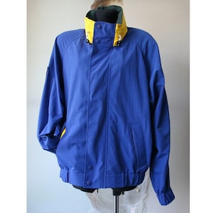 May include: A blue jacket with a yellow and green collar. The jacket has a zipper closure and two pockets.