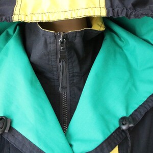 May include: A black hooded jacket with a green and yellow lining. The jacket has a zipper closure and a drawstring hood.