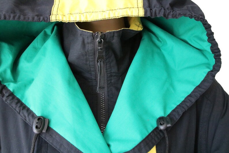 May include: A black hooded jacket with a green and yellow lining. The jacket has a zipper closure and a drawstring hood.