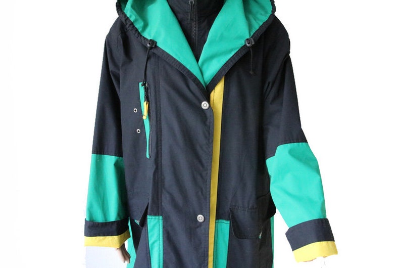 May include: A black hooded jacket with green and yellow accents. The jacket has a zipper closure and a button closure. The hood has a drawstring.