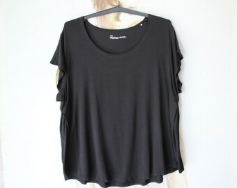 May include: A black short-sleeved t-shirt with a round neckline. The shirt has a relaxed fit and a slightly longer length.