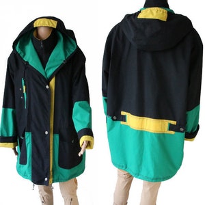May include: A black, green, and yellow hooded jacket with a zipper closure and two pockets. The jacket has a contrasting color design with a green and yellow panel at the bottom.