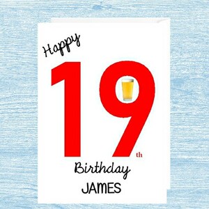 May include: A white card with red text that says "Happy 19th Birthday JAMES". The number 19 is in large red font. A small image of a glass of beer is inside the number 9.