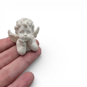 Mini Engel / Putte als gegossene Figur in der Hand – realistischer Größenvergleich der kleinen Engel-Deko mit feinen Details im Gesicht und in den Locken. Passend für DIY Gießprojekte und winterliche Weihnachtsdeko.