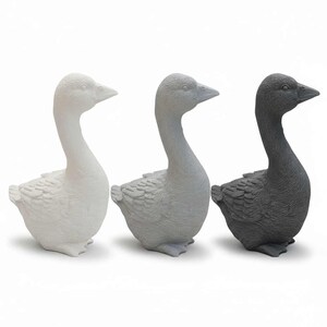 Drei Guss-Rohlinge der stehenden Gans nebeneinander in Weiß, Hellgrau und Dunkelgrau, Freisteller auf Weiß