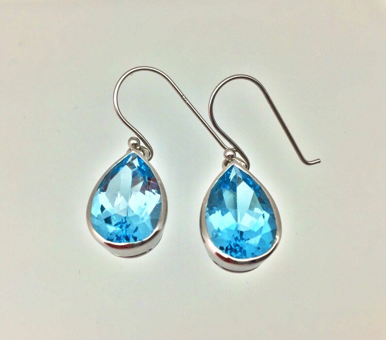 Puede incluir: Un par de pendientes de plata en forma de l&aacute;grima con piedras preciosas de topacio azul claro.
