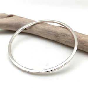 May include: A simple silver bangle bracelet with a smooth, polished finish.