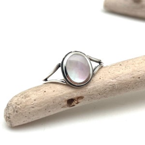 May include: A silver ring with an oval-shaped mother-of-pearl stone set in a bezel setting.