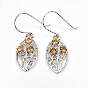 May include: A pair of silver earrings with a delicate leaf design and three small yellow gemstones.