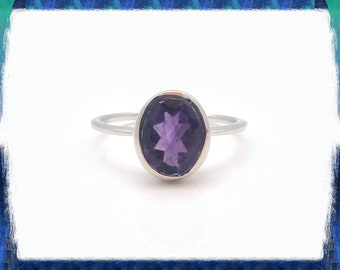 May include: A silver ring with a purple oval amethyst gemstone.