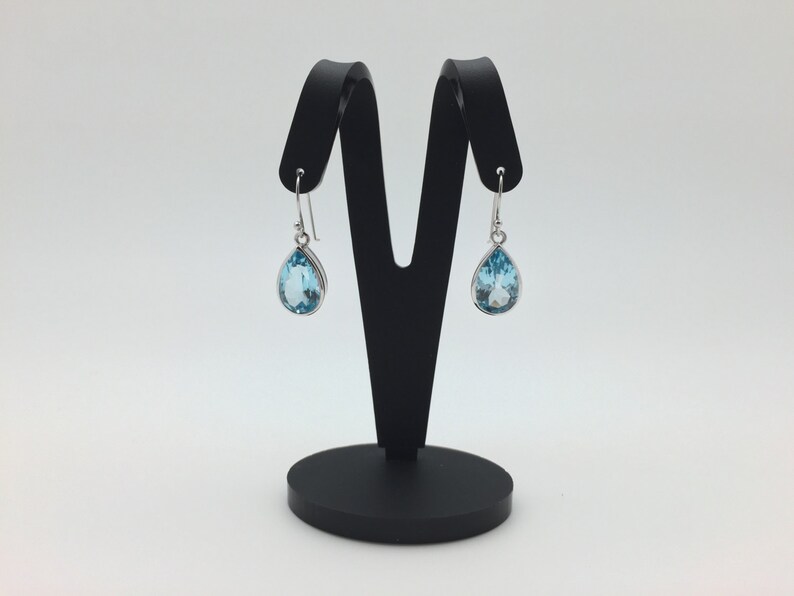 May include: A pair of silver teardrop earrings with light blue topaz gemstones.