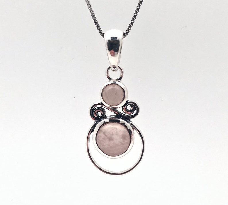 Peut inclure: Un collier avec un pendentif en argent avec deux pierres rondes rose p&acirc;le serties dans un motif en spirale.