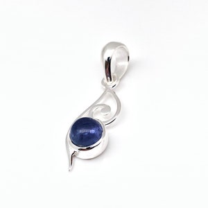 Op de afbeelding: Een zilveren hanger met een blauwe edelsteen in een swirl-ontwerp.