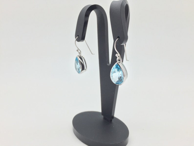 May include: A pair of silver teardrop earrings with light blue topaz gemstones.