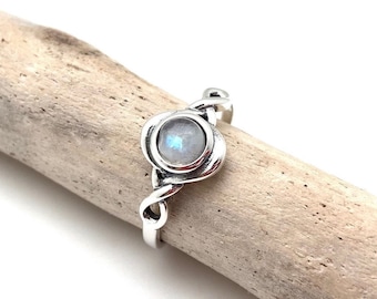 May include: A silver ring with a round moonstone set in a twisted band.
