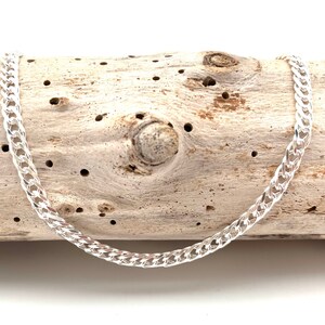May include: A silver curb chain necklace with a classic design. The chain is made of polished silver and has a smooth, shiny finish.