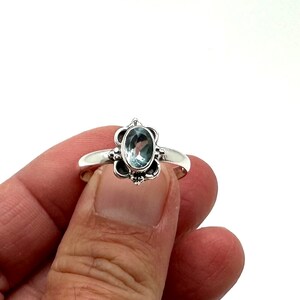 May include: A silver ring with a light blue oval gemstone set in a floral design.