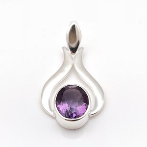 May include: A silver pendant featuring a purple amethyst gemstone. The pendant has a distinctive, flowing design.