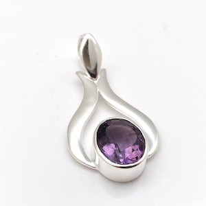 May include: A silver pendant featuring a purple amethyst gemstone set in a delicate, flowing design.